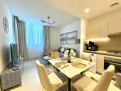 a kitchen and living room with a table and chairs at New 1 bedroom in Sobha Hartland in Dubai