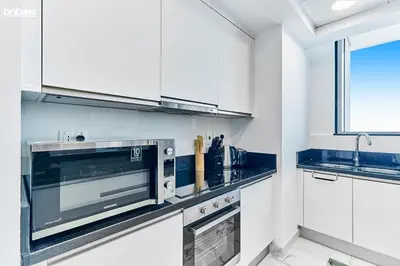 a kitchen with white cabinets and a microwave at bnbme - Luxury 2BR Business Bay Apt w Canal Views Pool Gym Free Parking Downtown in Dubai
