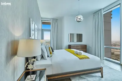 a bedroom with a white bed and a large window at bnbme - Luxury 2BR Business Bay Apt w Canal Views Pool Gym Free Parking Downtown in Dubai
