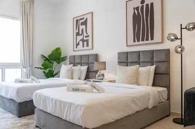 two beds in a hotel room with white walls at Spacious Serene Studio Retreat in JVC by Suiteable in Dubai