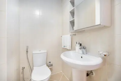 a white bathroom with a toilet and a sink at Spacious Serene Studio Retreat in JVC by Suiteable in Dubai