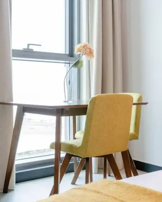 a desk with a chair and a vase with a flower on it at Stylish studio next to canal in Dubai