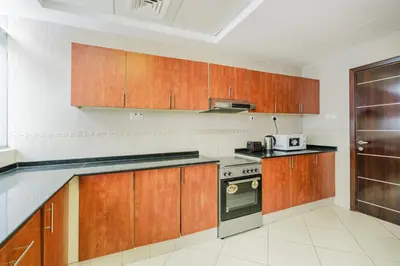 a kitchen with wooden cabinets and a stove at RH- Spacious, Stylish, 01BR near Mall of Emirates in Dubai