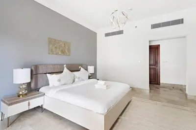 a white bedroom with a white bed and a table at StoneTree - Fairmont South 2 BR - Near Beach in Dubai
