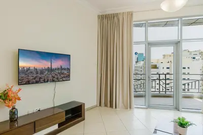 a living room with a tv and a large window at RH-Prime Location , Spacious 1 Bedroom near Mall of the Emirates in Dubai