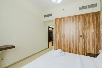 a bedroom with a white bed and a wooden door at RH-Prime Location , Spacious 1 Bedroom near Mall of the Emirates in Dubai