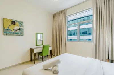 a bedroom with a bed and a desk and a window at RH- Huge, Comfortable 01 BR Apartment in Barsha1 in Dubai