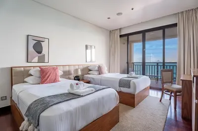 a hotel room with two beds and a balcony at GuestReady - A Glimpse of Burj Al Arab in Dubai