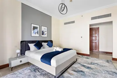 a white bedroom with a large bed with blue pillows at StoneTree - Golden Mile 4 2 BR - Supreme Residences in Dubai