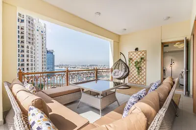 a living room with a couch and a table on a balcony at Marina Residences 2BR: Seaside in Palm Jumeirah in Dubai