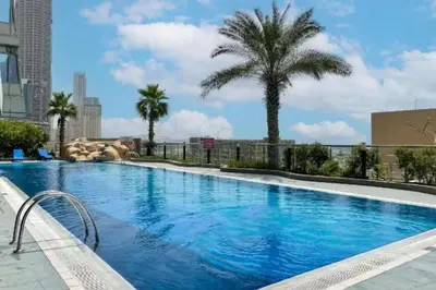 a large swimming pool with palm trees in a city at Ocean Heights - Gorgeous One Bedroom in Dubai
