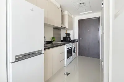 a kitchen with white cabinets and a refrigerator at Frank Porter - Carson A in Dubai