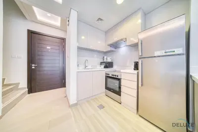 a kitchen with white cabinets and a refrigerator and a door at Magnificent 3BR Townhouse at DAMAC Hills 2, Dubailand by Deluxe Holiday Homes in Dubai