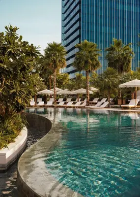 a swimming pool with chairs and palm trees and a building at SIRO One Za'abeel in Dubai