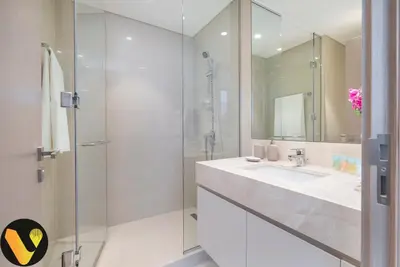 a white bathroom with a sink and a shower at Vogue Downtown Act Two near Burj Khalifa and Dubai Mall, Three Bedroom Plus Kids room Apartment with Balcony and Burj Khalifa View, Access to all Amenities in Dubai