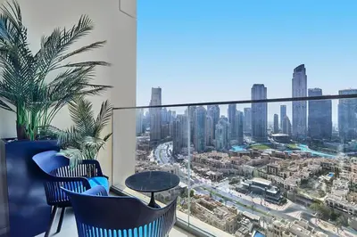 a balcony with blue chairs and a view of a city at FIRST CLASS 2BD, Full Burj Khalifa view in the Heart of Downtown in Dubai