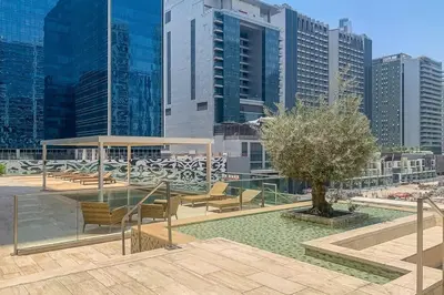 a park with benches and a tree in a city at Frank Porter - Majestine 1 in Dubai