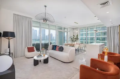 a living room with white furniture and a table at Elegant seaside living 3-bedroom Emaar Beachfront by Suiteable in Dubai