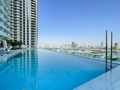 a large swimming pool with a view of a city at Elegant seaside living 3-bedroom Emaar Beachfront by Suiteable in Dubai