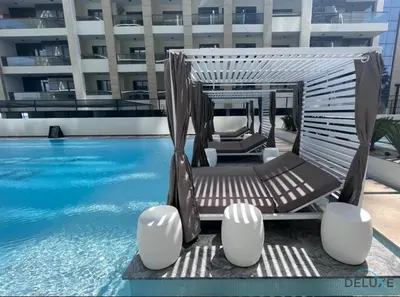 a swimming pool with two lounge chairs next to a building at Pristine 1BR at Binghatti Creek Al Jadaf by Deluxe Holiday Homes in Dubai