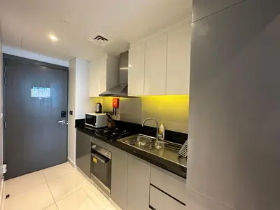 a kitchen with white cabinets and a sink and a stove at Business Bay Modern studio with a Canal view at DAMAC Maison Prive 1616 in Dubai