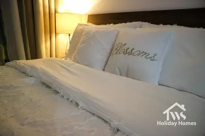 a bed with white sheets and pillows with theitched black remembered at The Urban Oasis - Bliss in Dubai