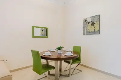 a dining room with a table and green chairs at RH - Spacious & Bright 01BR, Walk away to mall of Emirates in Dubai