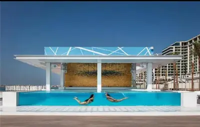 two people laying on the side of a swimming pool at Five Palm Super Luxury Apt with Full Sea Views in Dubai