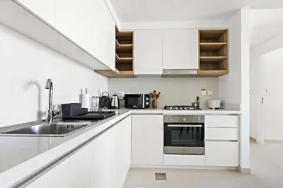 a white kitchen with white cabinets and a sink at Silkhaus chic 1BDR in the heart of Downtown in new tower in Dubai