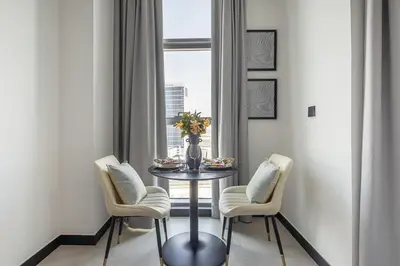 a table with three chairs and a vase with flowers on it at Frank Porter - 15 Northside Tower 1 in Dubai