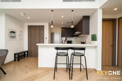 a kitchen with a counter and two bar stools at Pristine Cozy One Bedroom Suite in Dubai
