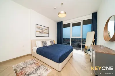 a bedroom with a bed and a television with a window at Pristine Cozy One Bedroom Suite in Dubai