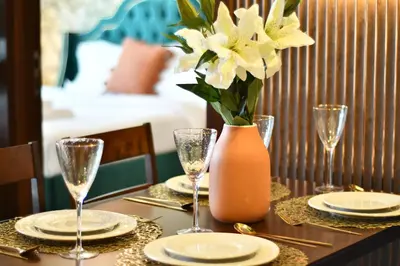 a table with glasses and a vase with flowers on it at Vera Residence-Canal Viewing Dubai Mall walking 2BR Chic APT in Dubai