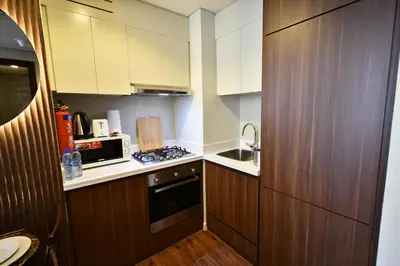 a small kitchen with wooden cabinets and a microwave at Vera Residence-Canal Viewing Dubai Mall walking 2BR Chic APT in Dubai