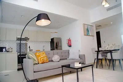 a living room with a couch and a kitchen at Green community - Tennis, streetball - 15 mins sea in Dubai