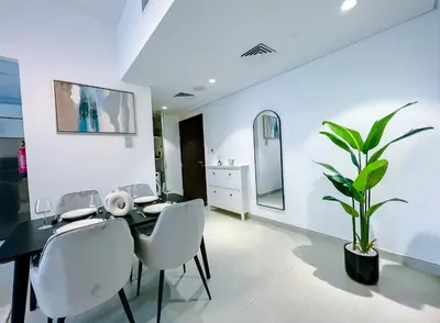 a dining room with a table and chairs and a plant at Green community - Tennis, streetball - 15 mins sea in Dubai