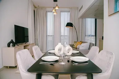 a dining room table with white chairs and a television at Green community - Tennis, streetball - 15 mins sea in Dubai