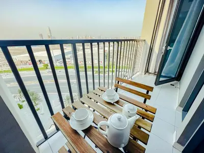 a balcony with a wooden table with cups and teapots on it at Green community - Tennis, streetball - 15 mins sea in Dubai
