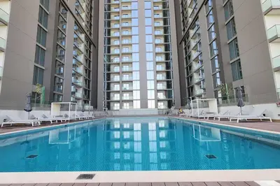 a large swimming pool with chairs and some buildings at STAY BY LATINEM Luxury 1BR Holiday Home CVR A702 near Burj Khalifa in Dubai