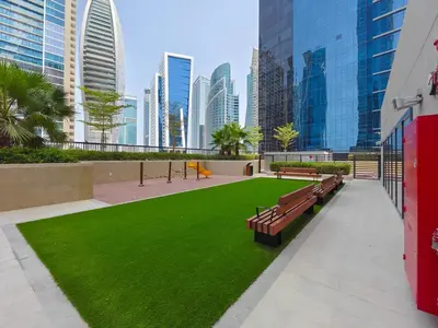 a park with benches and green grass in a city at Business Bay's Coziest Hideaway With Balcony in Dubai