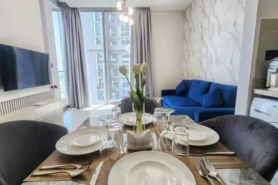 a dining room table with plates and glasses and a blue couch at STAY BY LATINEM Luxury 1BR Holiday Home CVR A703 near Burj Khalifa in Dubai
