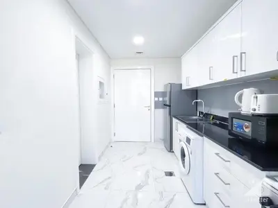 a kitchen with white cabinets and a microwave at Spacious Studio with balcony in AL Majan in Dubai