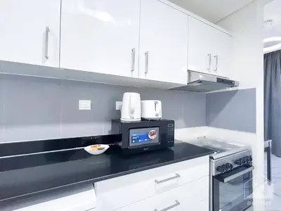 a kitchen with white cabinets and a microwave at Spacious Studio with balcony in AL Majan in Dubai