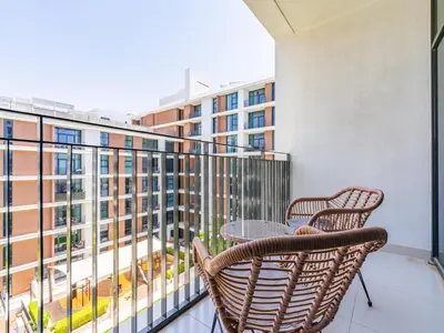 a balcony with two chairs and a table with a view of a building at Dazzling 1BR in Park Point - Dubai Hills in Dubai