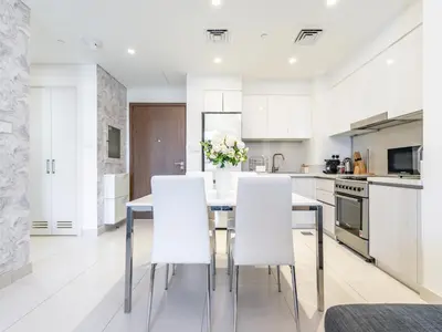 a kitchen with white cabinets and a table with white chairs at Dazzling 1BR in Park Point - Dubai Hills in Dubai