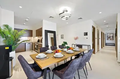 a dining room and kitchen with a wooden table and chairs at Extravagant 3BR + kid's room w/ Burj Khalifa view in Dubai