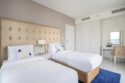a bedroom with two beds and a blue rug at Frank Porter - Damac Voleo in Dubai