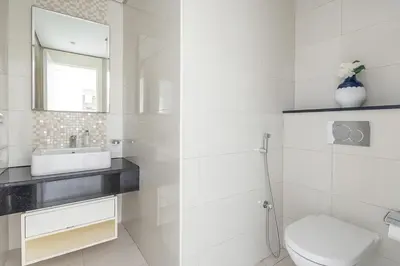 a white bathroom with a toilet and a sink at Frank Porter - Damac Voleo in Dubai