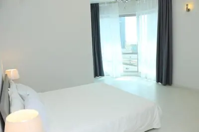 a white bedroom with a bed and a large window at Dubai Marina larivera in Dubai