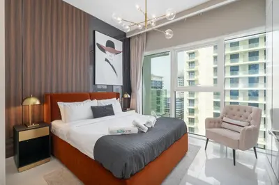 a bedroom with a bed and a chair and a window at Sunrise Bay with treasure stunning harbour view by Suiteable in Dubai